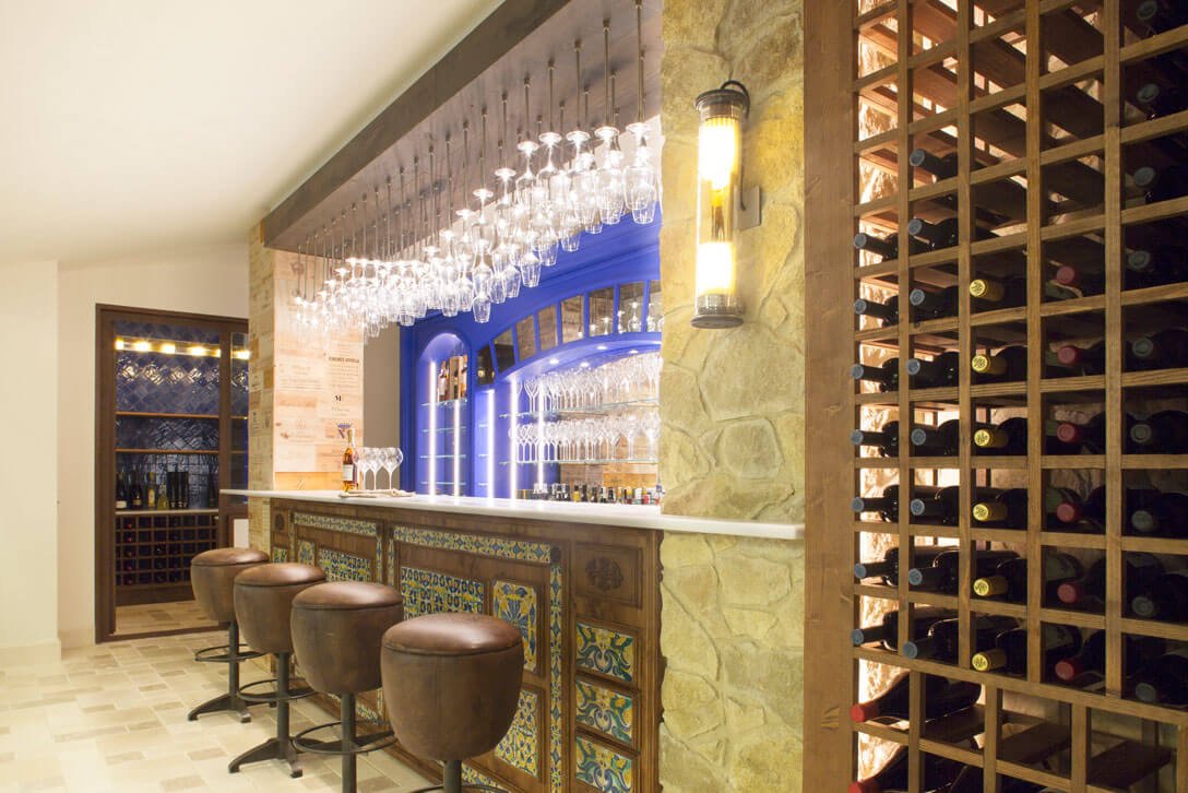 Celler interior amb barra revestida en fusta i ampoller en habitatge de la Costa Brava