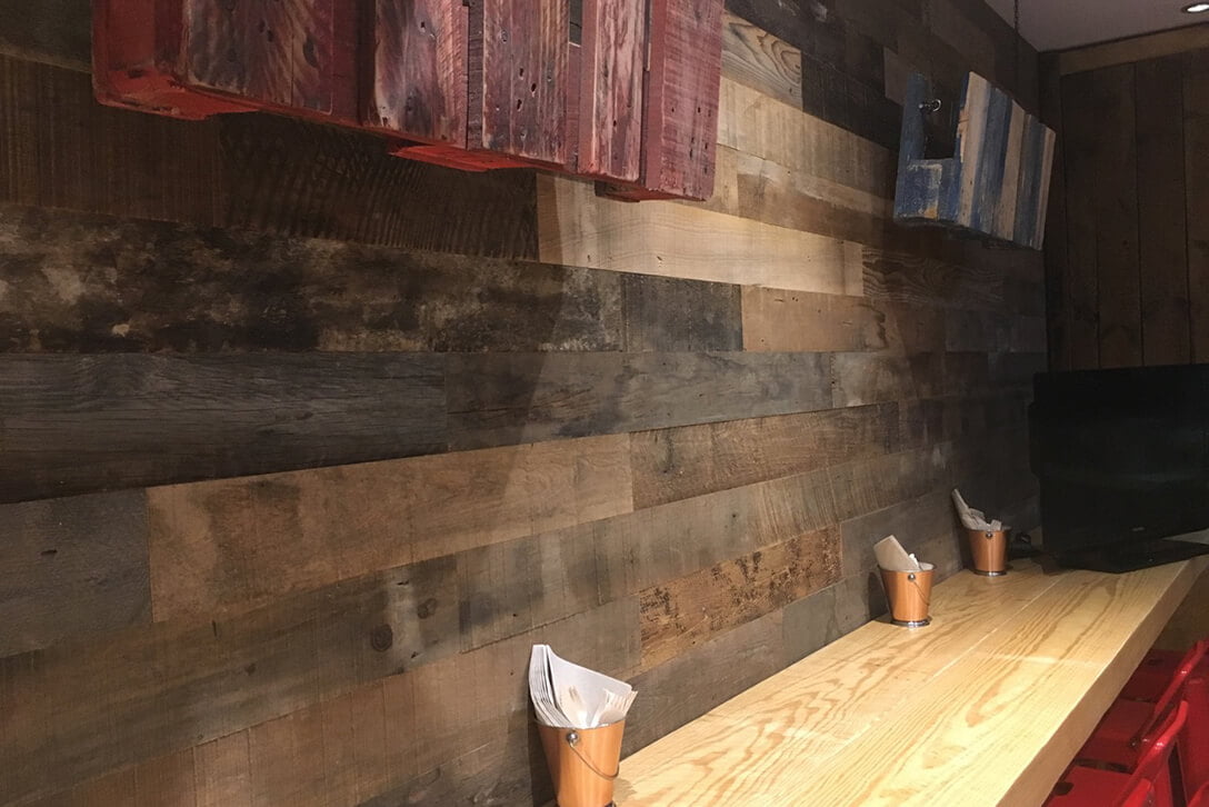 Revestimiento de paredes con madera mecanizada y acabado natural en restaurante de Barcelona.